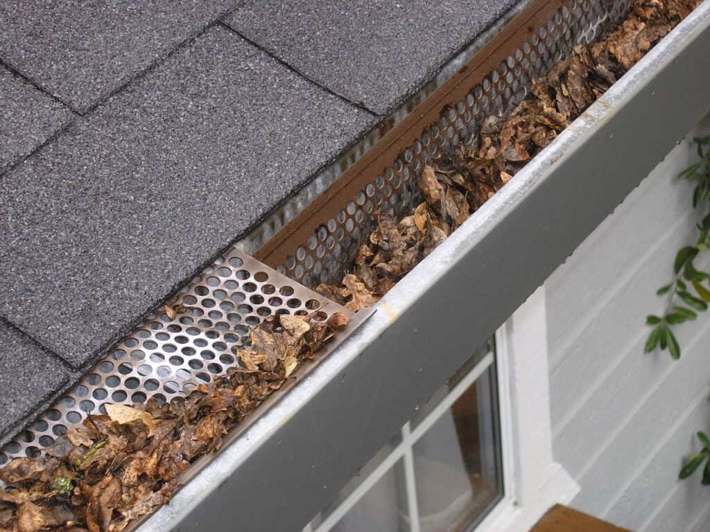 How Often Should Gutters be Cleaned? - Gutters on a House Full of Leaves and Debris
